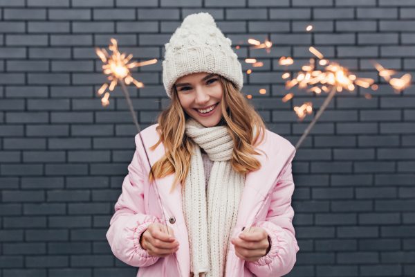 Smiling woman celebrating New Year with healthy teeth and sparklers