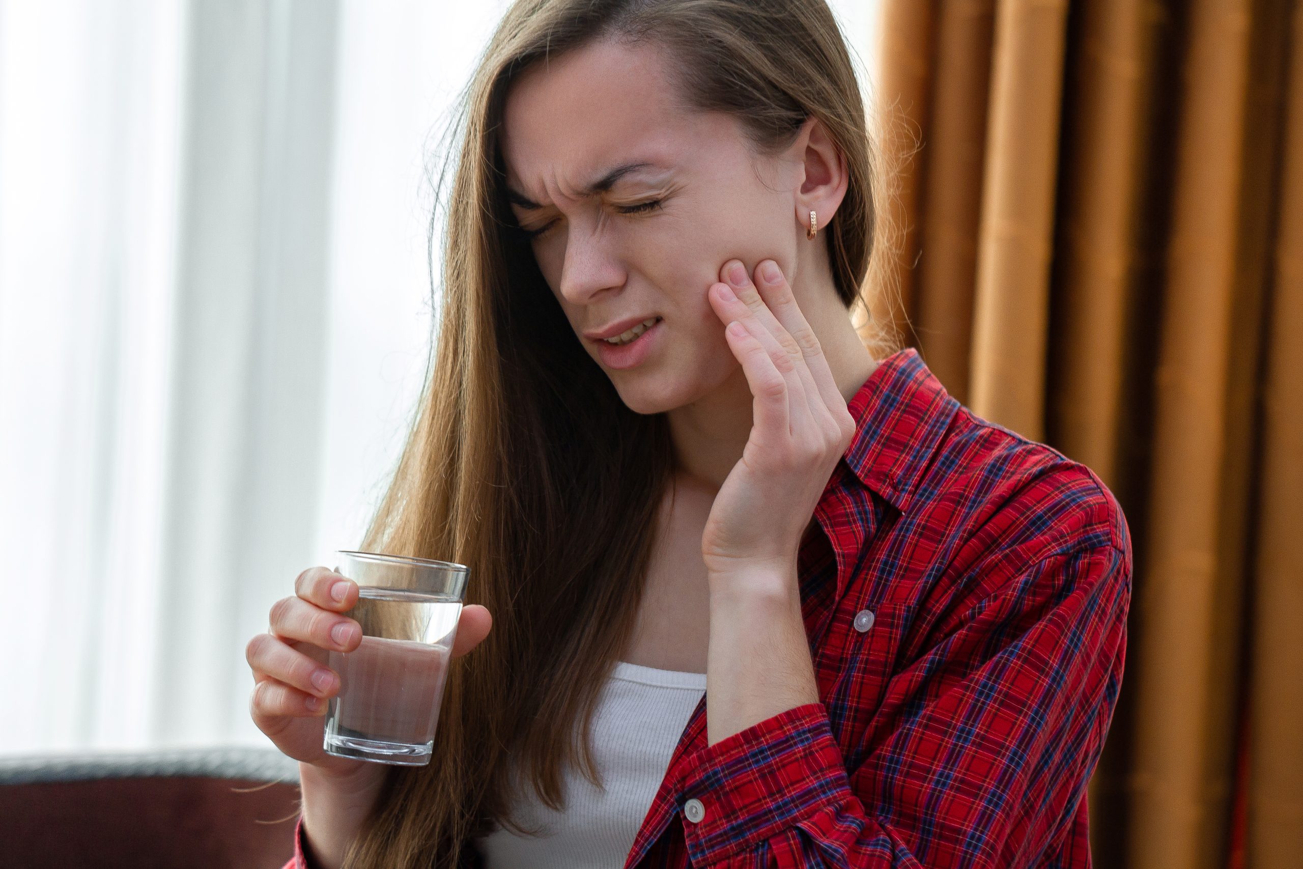 Close-up of woman reacting to cold drink with tooth sensitivity